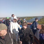 Grupa uczniów ogląda panoramę lasów i jeziora widoczną z Mysiej Wieży w Kruszwicy. 