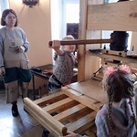 Dwoje uczniów obsługuje starą maszynę drukarską.