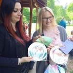 Dwie uśmiechnięte mamy prezentują pomalowane talerze otrzymane w prezencie od swoich dzieci.
