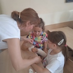 Pani pielęgniarka pokazuje dwóm uczennicom jak należy prawidłowo opatrywać kciuk.