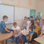 Pani pielęgniarka pokazuje sposób opatrywania stawu skokowego bandażując nogę uczniowi.