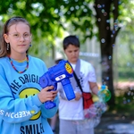 Dziewczynka ubrana w niebieską bluzę puszcza bańki.