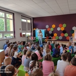 Grupa uczniów siedzi na podłodze i słucha opowieści pisarki.