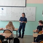 Pani policjantka prowadzi wyklad stojac na wprost siedzacych w ławkach uczniow klasy 6b.