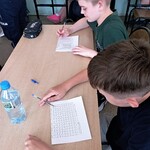 Uczniowie siedzący przy ławce rozwiązują zadania dotyczące właściwego zachowania.