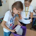 Dziewczynka moczy kartkę w misce_ koleżanka obok przyglada się z zaciekawieniem.jpg