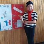 dziewczynka przebrana za Francuskę stoi obok plakatu Francji.jpg