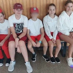 sześcioro dzieci w stojach biało czerwonych siedzi na ławce.jpg