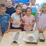 Uczniowie prezentują przygotowane do pieczenia blaszki z ciastem chlebowym.jpg