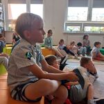 Uczniowie klasy 1d siedzą w bibliotece na pufach i dywanie. Słuchają głośnego czytania..jpg