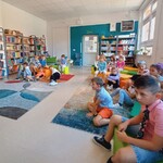 Uczniowie klasy 1d siedzą w bibliotece na pufach. Słuchają głośnego czytania..jpg
