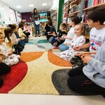 W bibliotece grupa cudzoziemskich uczniów siedzi naprzeciwko siebie. Uczestniczą w sprawnościowej zabawie..jpg