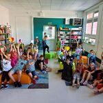 W bibliotece uczniowie klasy 2b siedzą na pufach w bibliotece.  Trzymają w podniesionych do góry dłoniach papierowe serca..jpg