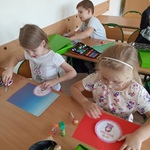 Dwie dziewczynki siedzą przy stoliku i wykonują papierowe medale.jpg