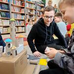 14 Uczniowie siedzą na dywanie i tworzą budowle z kartoników_ rolek po papierze. W tle półki z książkami..jpg