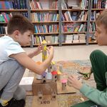 17 Uczniowie siedzą na dywanie i tworzą budowle z kartoników_ rolek po papierze. W tle półki z książkami..jpg