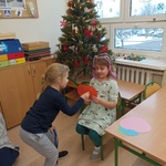 Dziewczynka przekłuwa papierowe serce trzymane przez koleżankę w klasie. W tle udekorowana choinka.jpg