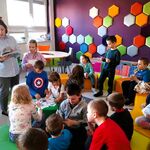 Zdjęcie 13 W bibliotece uczniowie klasy 1c siedzą na pufach. Naprzeciwko stoi Pani bibliotekarka i czyta książkę..jpg