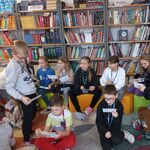Zdjęcie 19 W bibliotece uczniowie klasy 2a siedza na pufach. Oglądają pocztówki o uczuciach. W tle półki z książkami..jpg
