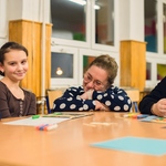 Dwie dziewczynki i nauczycielka pozują do zdjęcia. Na ławkach rozłożone są kartki do malowania i pastele olejne..jpg