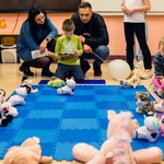 Grupa dzieci podczas zabawy robotami Photon. Na środku leży niebieska mata i ustawione są różne pluszaki..jpg