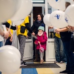 Grupa uczniów wita gości i wręcza im przygotowane mapy i balony..jpg