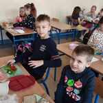 Dwójka chłopców siedzących przy stoliku wykonuje zdrowe kanapki.jpg