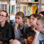 Zdjęcie 2 Uczniowie siedzą na pufach w bibliotece_ w tle półki z książkami..jpg