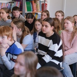 Zdjęcie 3 Uczniowie siedzą na ławeczkach w bibliotece_ w tle półki z książkami..jpg