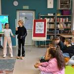 Zdjęcie 27 W bibliotece 2 ucznnice tańczą do muzyki_ Z tyłu stoi duzy ekran telewizora_ z boku na pufach siedzą uczniowie_.jpeg