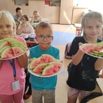 uczniowie trzymają talerze z kawałkami arbuza.jpg
