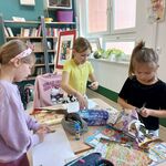 Zdjęcie 2 W bibliotece trzy uczennice stoją przy stoliku. Wycinają zdjęcia z gazet..jpg