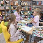 Zdjęcie 14 W bibliotece przy stoliku siedzą uczennice. Wycianją z gazet zdjęcia. W tle książki z półkami..jpg