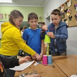 Dzieci budują wieżę z kubków papierowych i słomek_ pracując razem przy stole..jpg