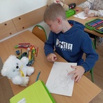 Chłopiec patrzy na swojego misia i rysuje jego portret na kartce..jpg