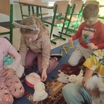 Dzieci na dywanie w klasie używające miarki krawieckiej do mierzenia swoich pluszowych zabawek..jpg