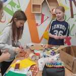 Grupa dziewcząt pracuje nad kreatywnym projektem z kartonu w sali edukacyjnej..jpg