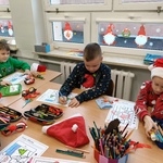 Dzieci w świątecznych strojach kolorują obrazki z Mikołajem w udekorowanej sali..jpg