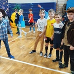 Grupa chłopców w ciekawych przebraniach_ m.in. kowboje_ piłkarze. W tle inni uczestnicy balu bawią się w sali gimnastycznej..jpg