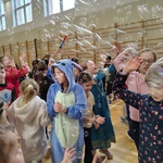 Grupa uśmiechniętych uczniów bawi się w czasie balu karnawałowego łapiąc bańki mydlane..jpg