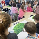 Grupa uczniów stojąca przy kartach z drzewami genealogicznymi.jpg
