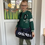 Chłopiec trzyma czarną torbę z napisem firmy addidas.jpg