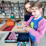 W bibliotece uczennice losują karteczki z pytaniami konkursowymi.jpg