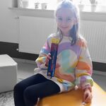 W bibliotece na pufie siedzi uczennica_ trzyma w ręku nagrodę_ długopis.jpg
