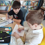 Dwaj chłopcy siedzący przy stoliku w bibliotece opisują wybrane przez siebie wiosenne rośliny.jpg