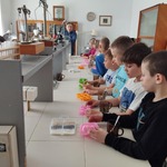 Grupa dzieci stoi przy stolikach w trakcie wykonywania mydełek .jpg