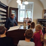 Pan oprowadzający po muzeum opowiada dzieciom o specyfice zawodu  farmaceuty.jpg
