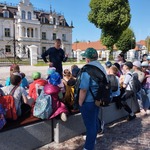 Dzieci obok Pałacu Buchholtzów w Supraślu słuchają pana przewodnika.jpg