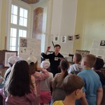 Dzieci w Muzeum Sztuki Drukarskiej i Papiernictwa w Supraślu słuchają przewodniczki mówiącej o Janie Gutenbergu.jpg