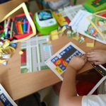 Dziecko przy stoliku układa elementy makiety ruchu drogowego  - znaki drogowe_ pojazdy..jpg